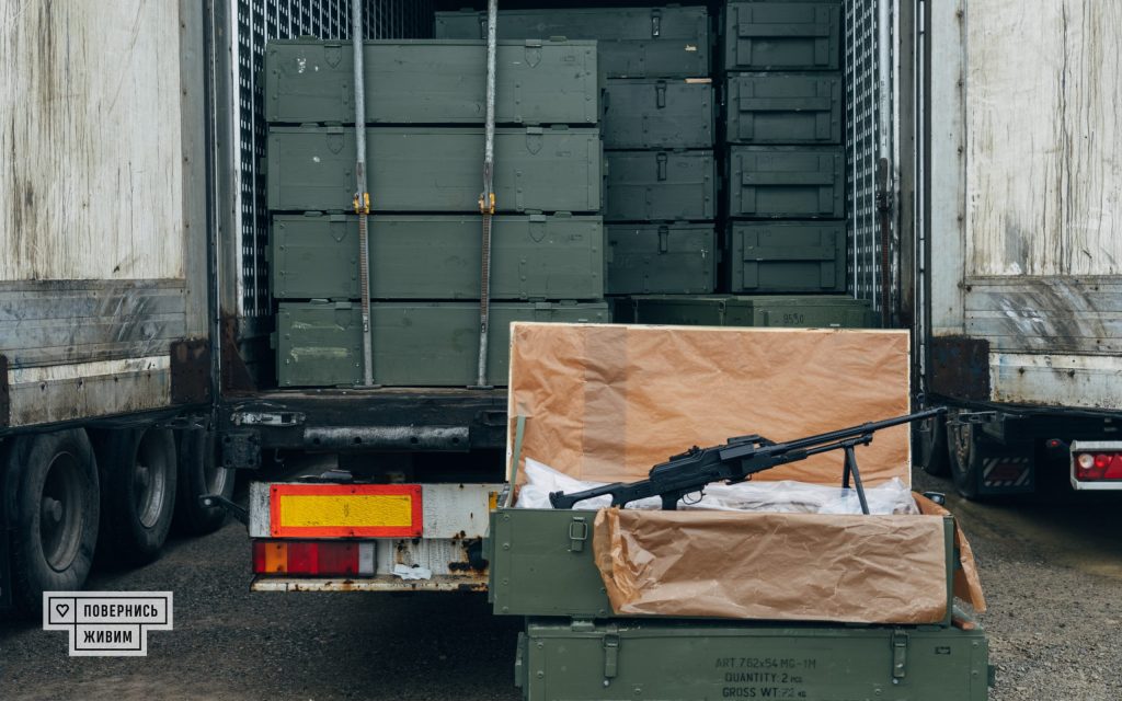 Розпакований кулемет у коробці на фоні вантажівки з рештою кулеметів