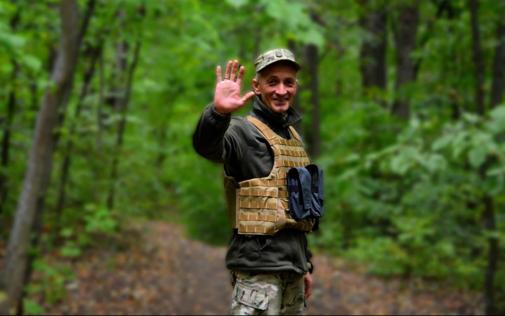 Військовослужбовець Владислав Косенко із піднятою у привітанні правою рукою у лісі