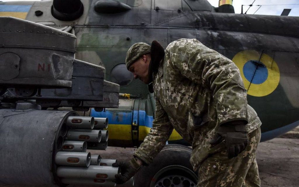 Чоловік у військовій формі на фоні військової техніки розмальованої у кольори українського прапора