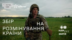 Жінка у військовій формі стоїть у полі на фоні хмарного неба